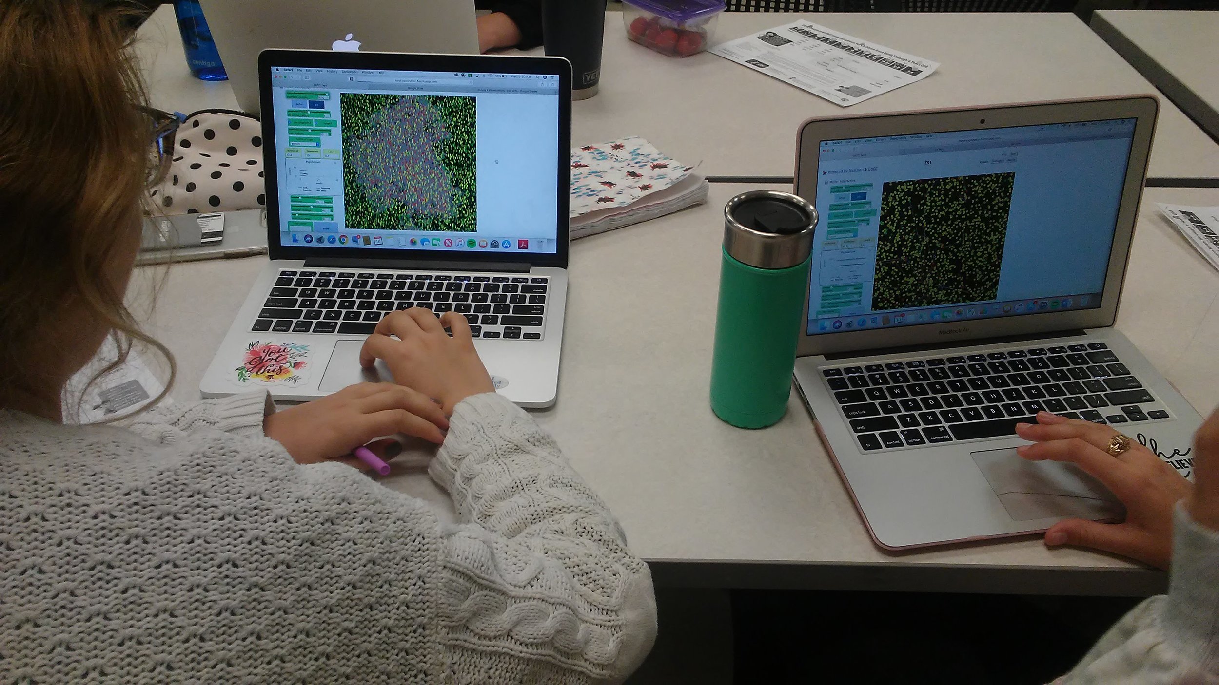 Two preservice elementary science teachers running simulations of measles spreading at varying densities and vaccination rates.